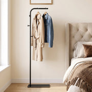 Black clothes rail with a coat and denim jacket in a bedroom beside a bed