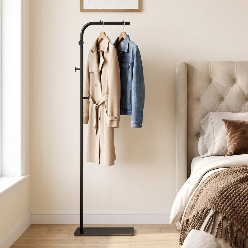 Black clothes rail with a coat and denim jacket in a bedroom beside a bed