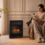 Black coal bed electric fireplace beside an armchair as a woman reads