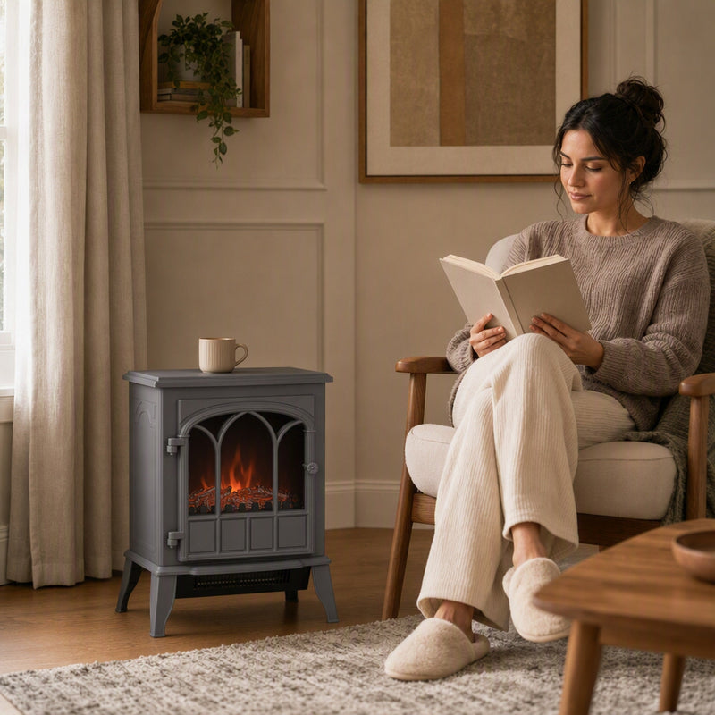 Compact electric fireplace on a rug beside a woman reading in a chair