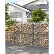Stone-filled gabion basket forming a garden boundary wall in front of a house