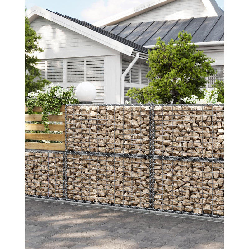 Stone-filled gabion basket forming a garden boundary wall in front of a house