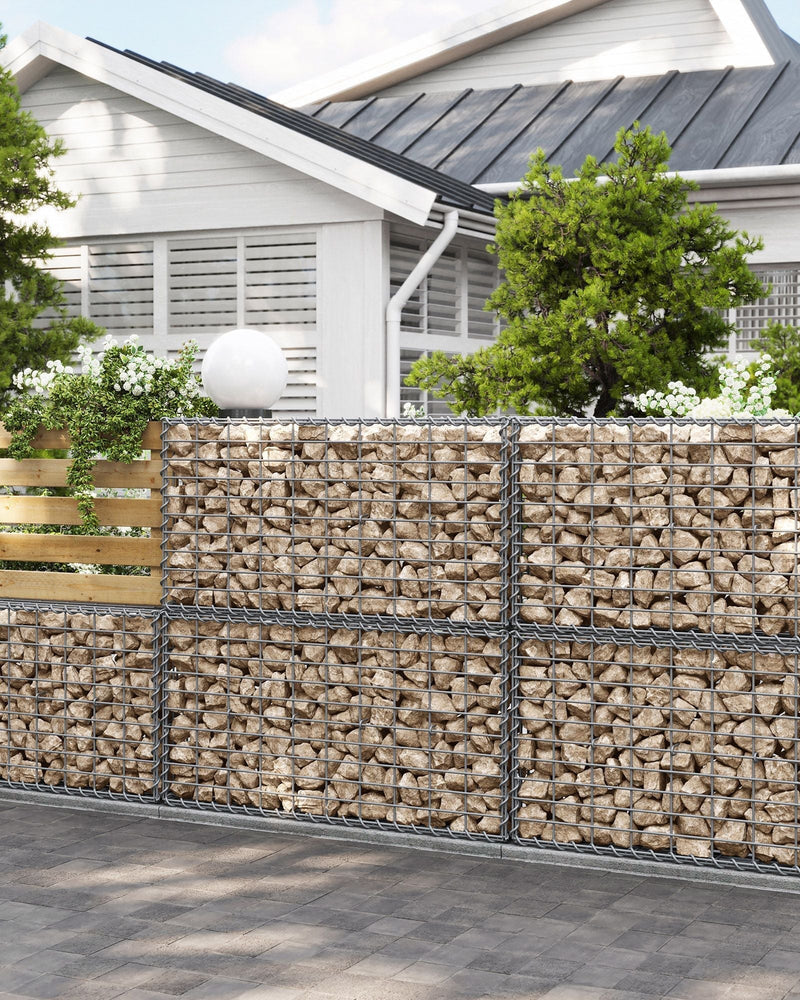 Stone-filled gabion baskets used as a garden boundary wall in front of a house