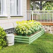 Light green raised garden bed with yellow and white flowers in front of a porch
