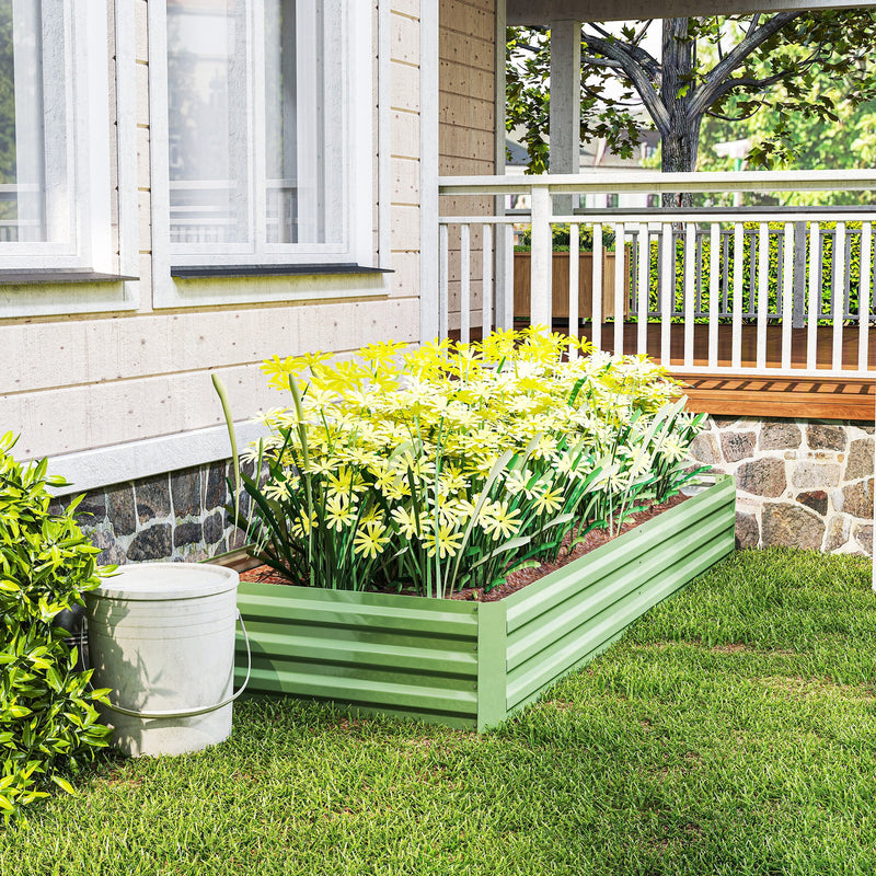 Light green raised garden bed with yellow and white flowers in front of a porch