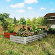 Silver raised garden bed planted with foliage and flowers next to an orange pot