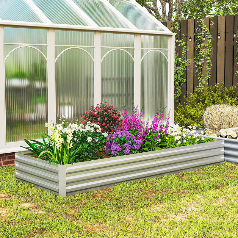 Silver raised garden bed with colourful flowers in front of a greenhouse
