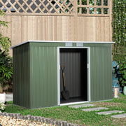 Green shed in a garden beside a trellis fence with a spade inside