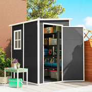 Lean to shed against a house wall with the door open, showing boxes and a hose stored inside