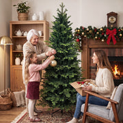 Grandmother and girl decorating the tree while a woman unpacks baubles nearby