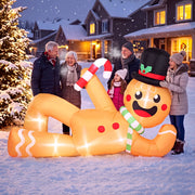 Family standing beside the giant lit gingerbread man on a snowy street