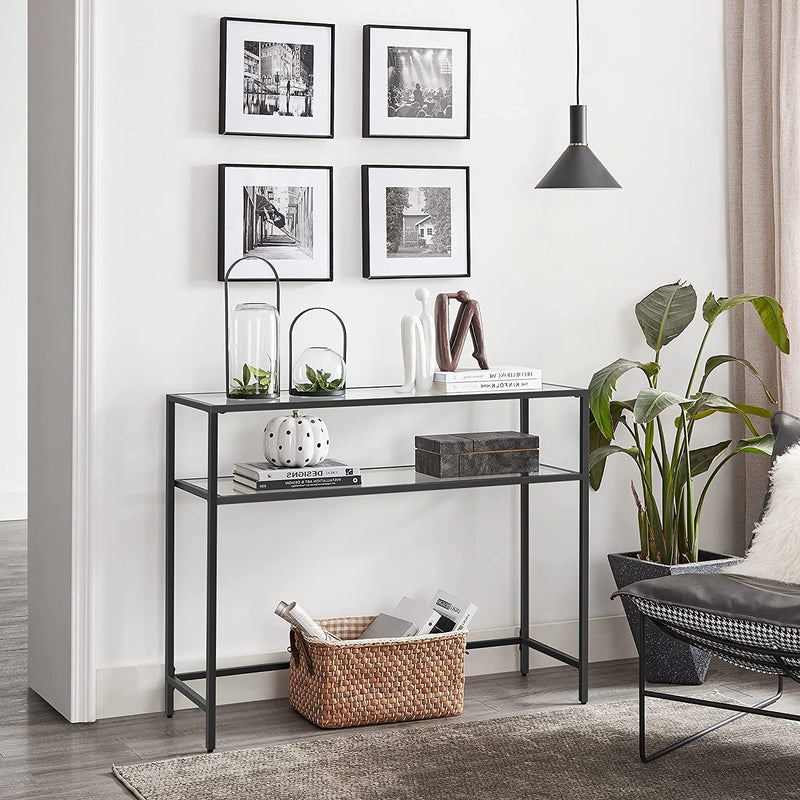 Black console table in a hallway beneath a gallery wall of framed prints