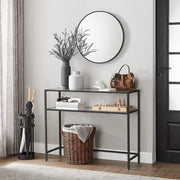 Black console table in an entryway with a round mirror and basket below