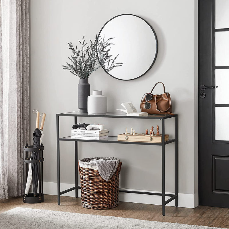 Black console table in an entryway with a round mirror and basket below