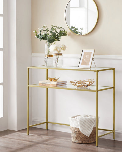 Gold console table in a hallway below a round mirror with flowers on top