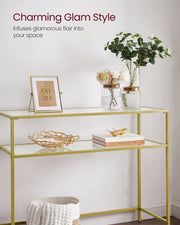 Gold console table styled with picture frames and a bowl on the glass top
