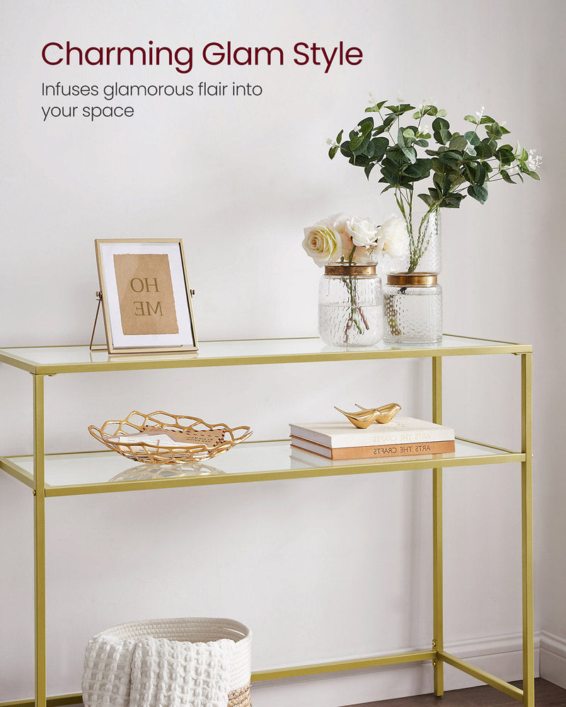 Gold console table styled with picture frames and a bowl on the glass top
