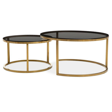 Gold and glass round nesting coffee tables on a plain background
