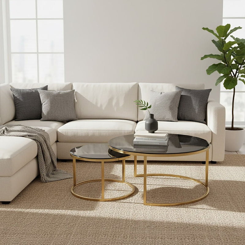 Gold and glass round nesting coffee tables styled beside a sofa