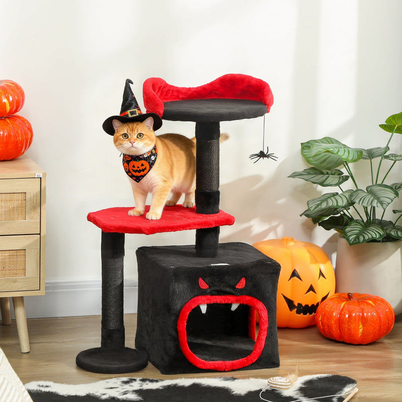 Cat wearing a witch hat sitting on the red top perch of the Gothic cat tree indoors with Halloween pumpkins