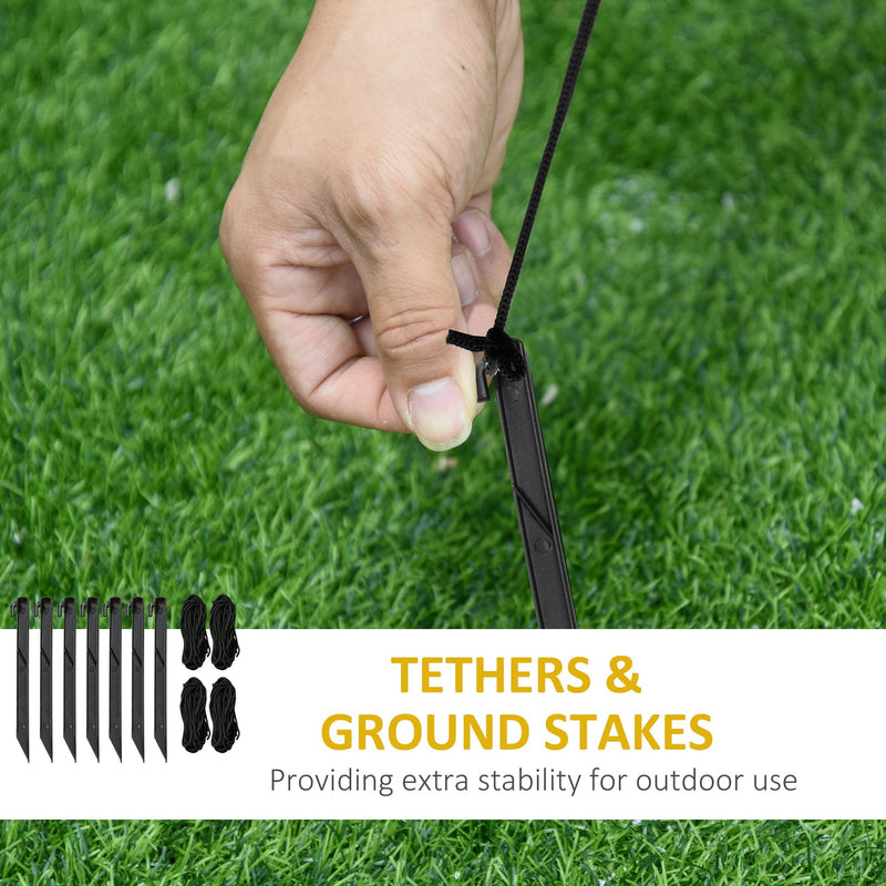 Seven ground stakes and four tethers, with a hand attaching a tether to a stake on grass