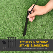 Hand pushing a black ground stake into grass with tethers and stakes callout