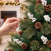 Hand holding white berries on a branch, with pine cones and golden-tipped needles on the 5ft tree