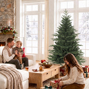 Family relaxing by the tree in a bright living room while a woman arranges gifts