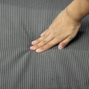 Close-up of a hand pressing into the corduroy seat cushion