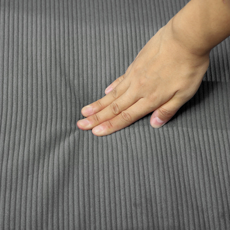 Close-up of a hand pressing into the corduroy seat cushion