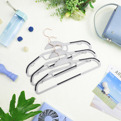 Grey hangers with rose gold hooks laid flat among lifestyle desk items