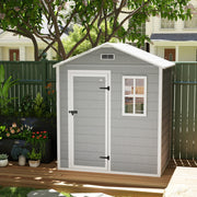 Grey plastic garden shed on decking beside a dark fence with the door closed