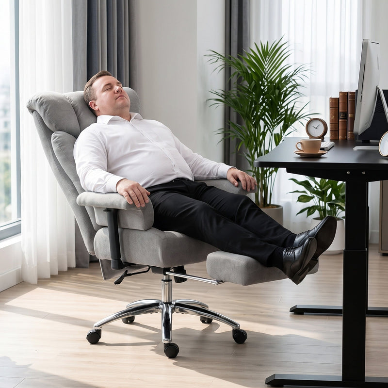 Man resting in the reclined grey office chair with his feet on the footrest