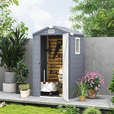 Grey plastic garden shed in a garden with the door open and hand tools hung inside