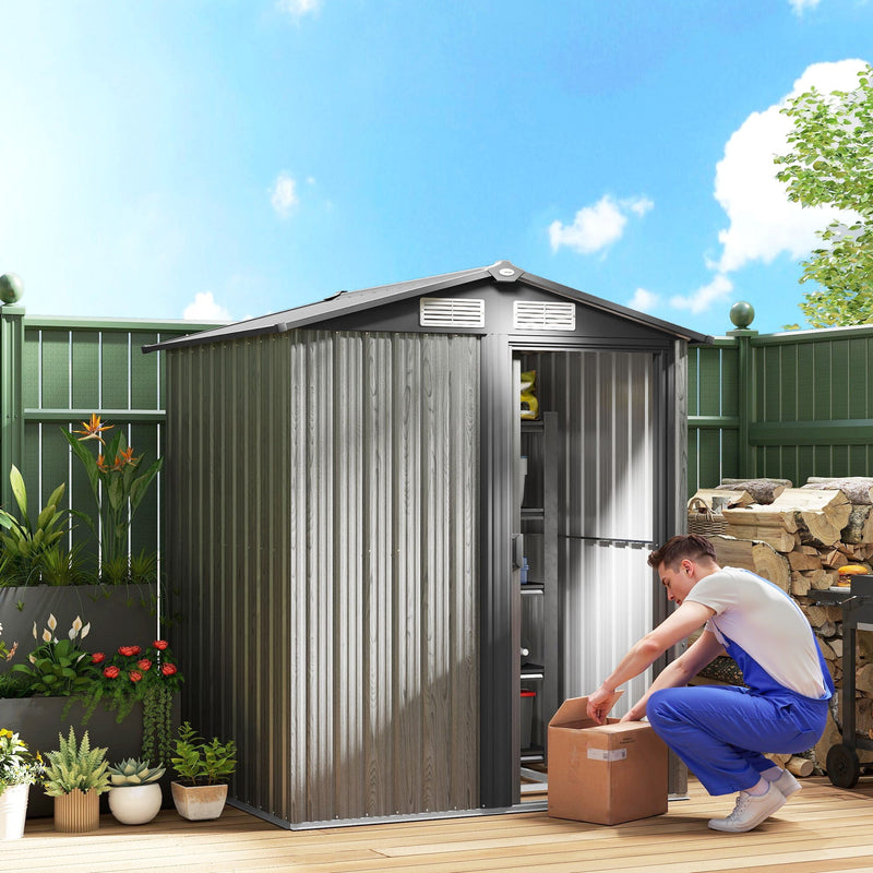 Grey wood effect metal shed on decking with the sliding door open and a man packing a box