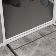 Close-up of the shed floor panel meeting the white door sill on stone paving