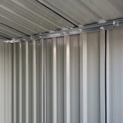 Interior view along the shed's corrugated steel side wall and the roof rail running above it