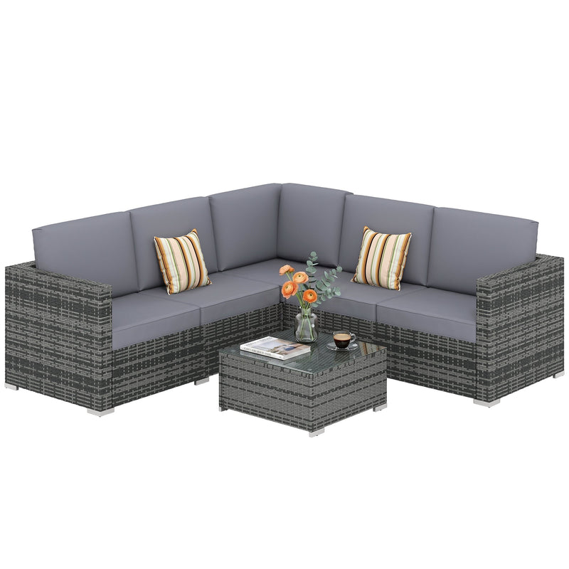 Grey rattan corner sofa set with grey cushions and glass coffee table on a white background