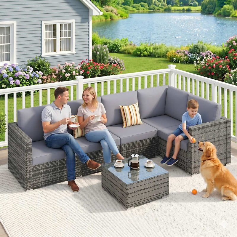 Family and dog relaxing on the rattan corner sofa set on a decking by a lake