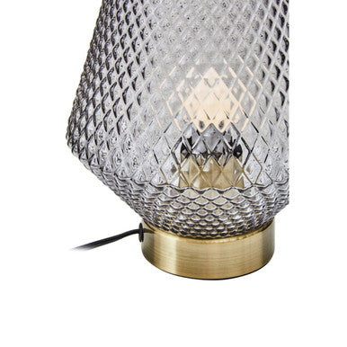 Close-up of gold ring base on grey smoked glass table lamp