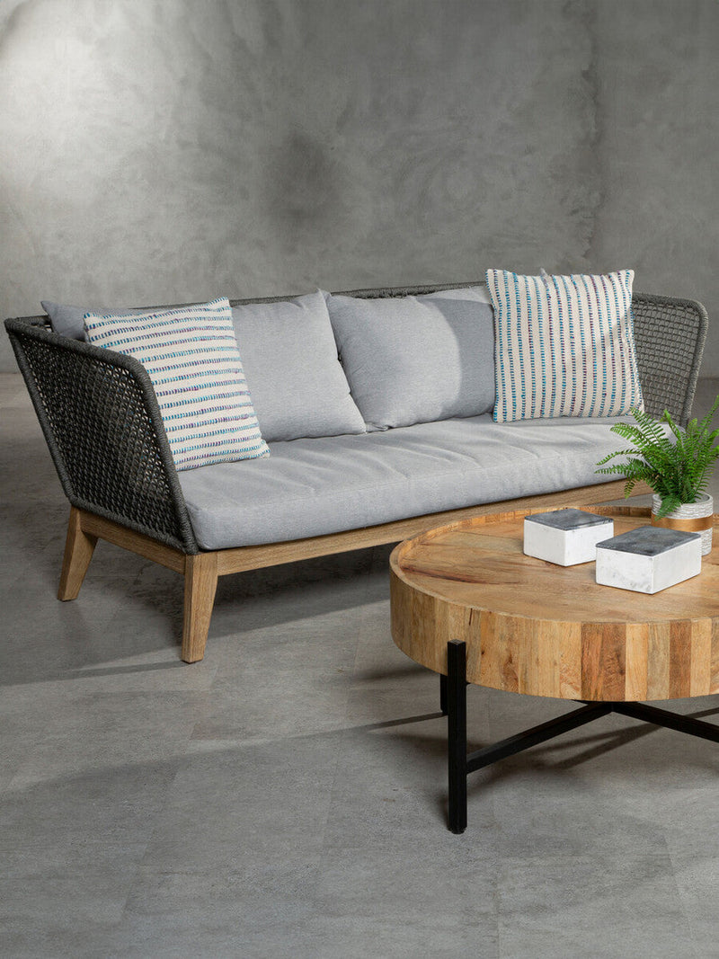 Grey woven rope sofa styled with cushions in a lounge setting