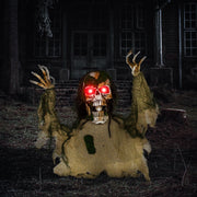 Half-body skeleton prop with glowing red eyes displayed outside a haunted house at night