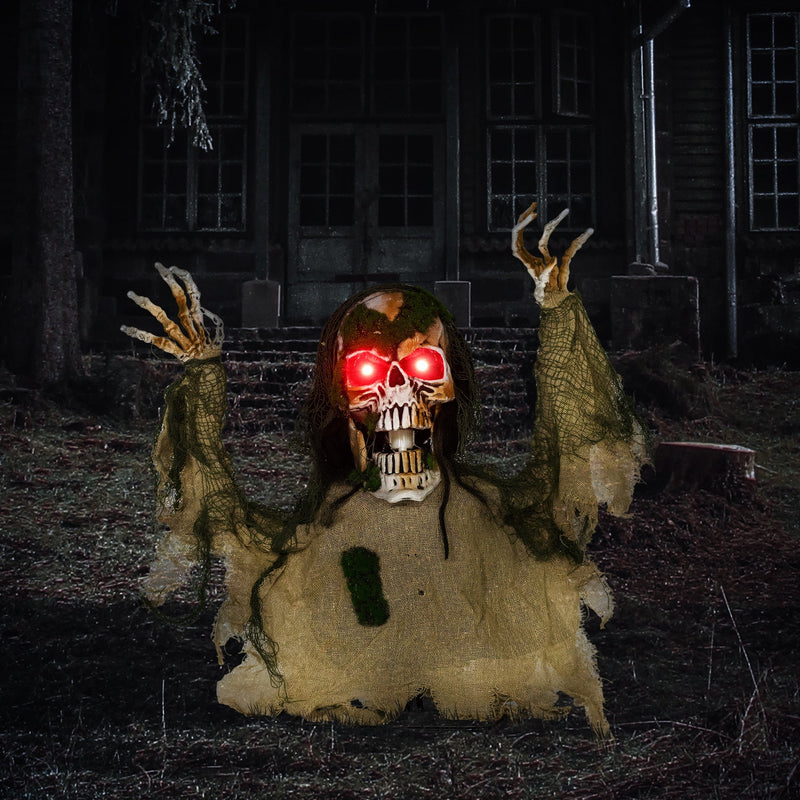 Half-body skeleton prop with glowing red eyes displayed outside a haunted house at night