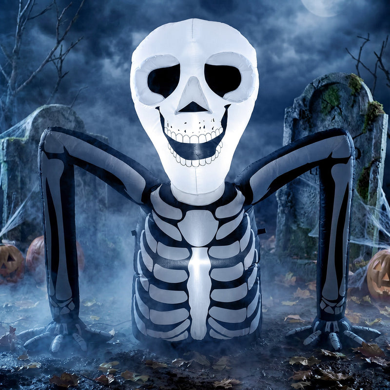 Ground crawling skeleton inflatable lit up at night among gravestones and pumpkins