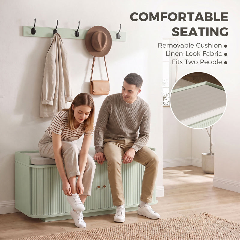 Two people sitting on the light green shoe bench's removable linen-look cushion while putting on shoes