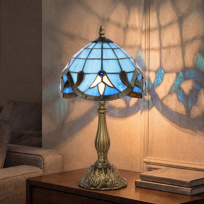 Lit fleur pattern lamp on a side table casting a glass pattern onto the wall