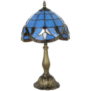 Stained glass table lamp with a fleur pattern shade on an ornate base, studio shot