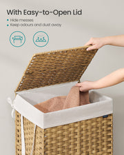 A hand lifting the hinged woven lid to drop clothing into the white liner inside the basket
