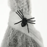 Close-up of a black plastic spider sitting on the white cocoon webbing
