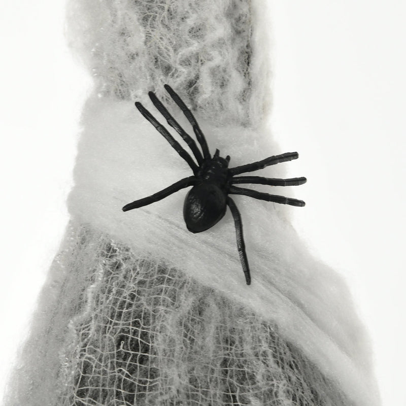 Close-up of a black plastic spider sitting on the white cocoon webbing